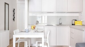 A modern kitchen with white cabinetry, a dining table with chairs, a coffee maker, and a yellow toaster. - The apartment is located in the historic center just three minutes from the fountain of Neptune and a short walk from all the most important artistic and culinary destinations of the city.In this neighborhood you can breathe a ville lumière atmosphere (Bologna)