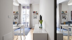 A modern, well-lit room with a dining table, chairs, a white cabinet, and a large window with curtains. - The apartment is located in the historic center just three minutes from the fountain of Neptune and a short walk from all the most important artistic and culinary destinations of the city.In this neighborhood you can breathe a ville lumière atmosphere (Bologna)