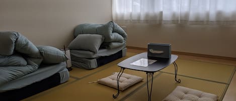 Una habitación tradicional japonesa con suelo de tatami, una mesa baja con una computadora portátil y cojines en un sofá.