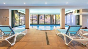 An indoor swimming pool with two lounge chairs and a view of the outside. - VILLA CIRCE - Exclusive villa with indoor heated pool in Fornalutx. (fornalutx)