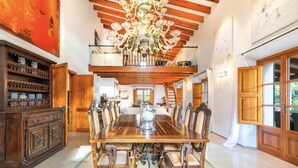 A spacious dining area with a large wooden table and chairs, a chandelier, and a wooden cabinet with decorative items. - VILLA CIRCE - Exclusive villa with indoor heated pool in Fornalutx. (fornalutx)