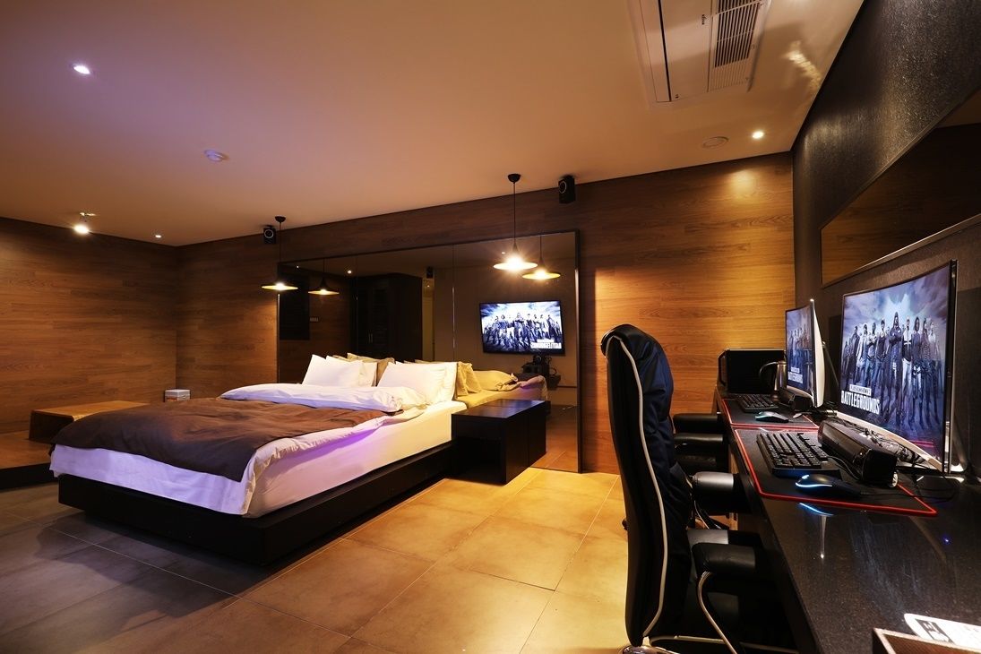 A modern bedroom with a large bed, a desk with a computer, and a TV.