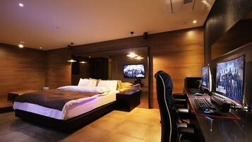 A modern bedroom with a large bed, a desk with a computer, and a TV.
