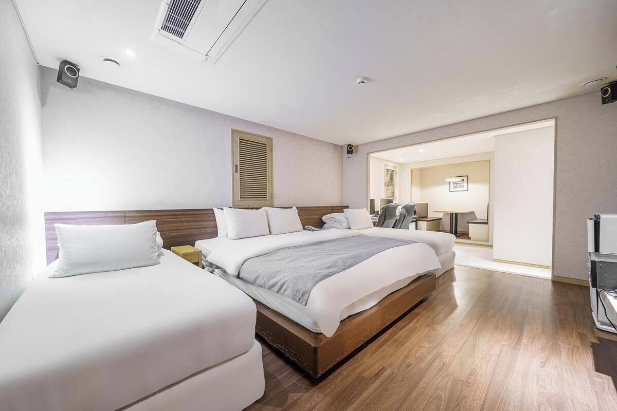A hotel room with a large bed, a smaller bed, a desk, a chair, and a television.
