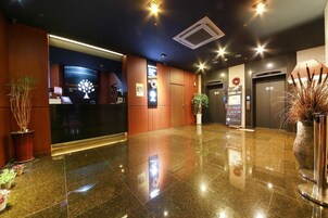 Un hall de hotel con mostrador de recepción, cafetería y ascensor.