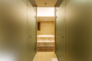 Un pasillo estrecho con suelo de baldosas que conduce a un baño con zona de ducha.