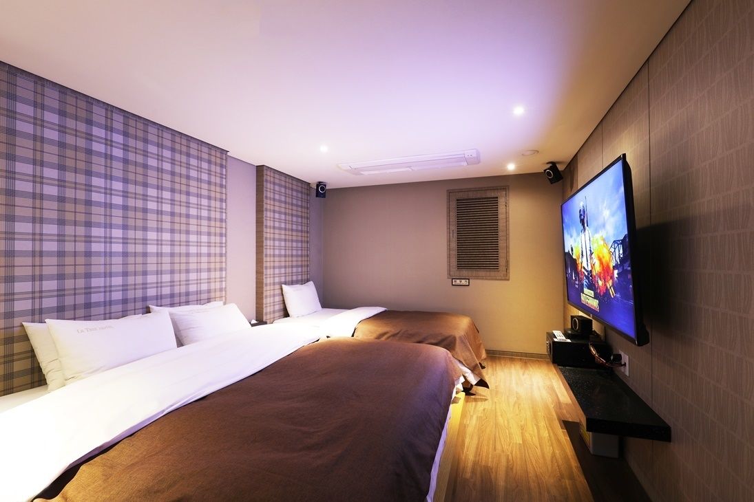 A hotel room with two beds, a television, and a wall-mounted speaker.