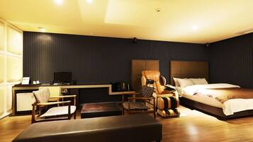 Una habitación de hotel moderna con cama, escritorio, silla y sofá.
