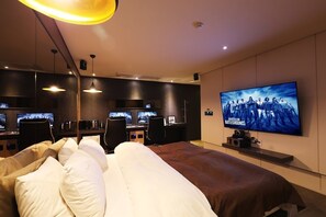 A modern hotel room with a large bed, a desk with two monitors, and a TV displaying a movie. - Uijeongbu La Tree Hotel (Uijeongbu)
