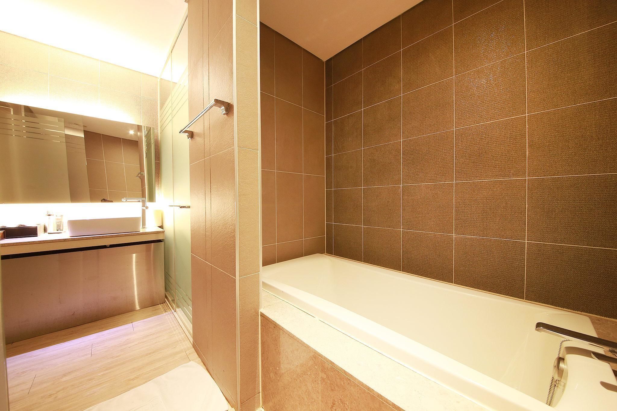 Une salle de bain moderne avec une baignoire, un meuble-lavabo avec un miroir et des murs carrelés.