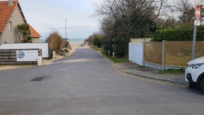 A street leading to a beach with a sign for 'Locations Meublées' and a no entry sign for bicycles.