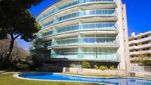 A multi-story hotel with a curved facade, balconies, and a swimming pool in the foreground. - Apartment in the city centre, with pool and A/C (Salou)