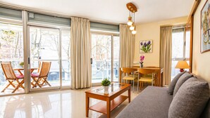 A modern living room with a sofa, a coffee table, and a dining area with chairs and a table. - Apartment in the city centre, with pool and A/C (Salou)