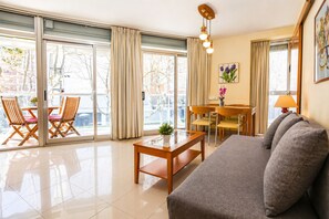 Een moderne woonkamer met een bank, een salontafel, en een eethoek met stoelen en een tafel.