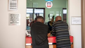 Un mostrador de recepción con un letrero de punto de acceso Wi-Fi, un aviso de seguridad y un reloj en la pared.