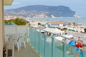 A balcony with a table and chairs, a view of the sea and a mountain, and a restaurant sign. - M062 - Marcelli, seafront penthouse (Marcelli)