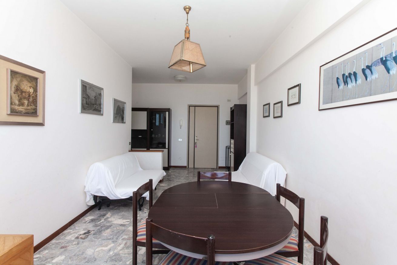 Zona pranzo con tavolo rotondo, sedie, lampadario e opere d'arte alle pareti.