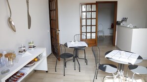 A dining area with a white table set for four, black chairs, and a wooden door in the background. - Simonetta's Rooms (Noto)