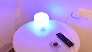 A white table with a remote control and a small glass container. - Simonetta's Rooms (Noto)