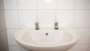 A white bathroom sink with two faucets and a drain. - Ecomotel O.R Tambo Intl (Kempton Park)