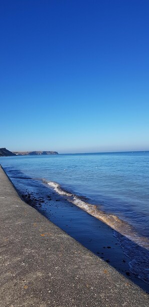 A coastal walkway with a clear view of the ocean and distant landforms. - New house near the beaches of the landing (Saint-Côme-de-Fresné)