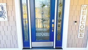 A blue front door with a glass panel, a welcome sign, and a doormat. - Luxury 4Bedroom/ 4 Bath with Private Salt-Water Pool! (North Myrtle Beach)