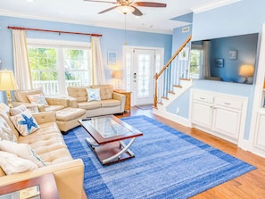 A living room with a sofa set, a coffee table, a TV, and a staircase.
