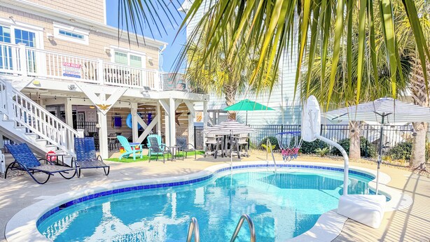 A swimming pool with a sun deck, lounge chairs, and a covered seating area. - Luxury 4Bedroom/ 4 Bath with Private Salt-Water Pool! (North Myrtle Beach)