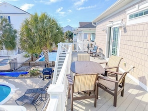 A deck with outdoor furniture, a pool, and a view of neighboring houses.