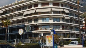 A multi-story hotel with balconies, a visible sign for a hotel, and a parked car in front. - Seafront studio with terrace, near beaches and center, Free Wifi (Menton)