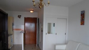A living room with a white sofa, a dining table, and a kitchen area with a washing machine. - Seafront studio with terrace, near beaches and center, Free Wifi (Menton)