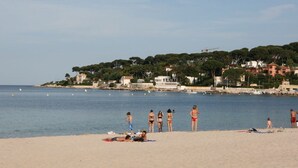 A beach with people sunbathing and swimming, a clear sky, and buildings in the background. - CHARMING T2 IN THE HEART OF THE OLD TOWN - QUIET - 100 M SEA AND MARKET (Antibes)