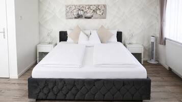 A neatly made bed with a dark headboard, white bedding, and two bedside tables with lamps.