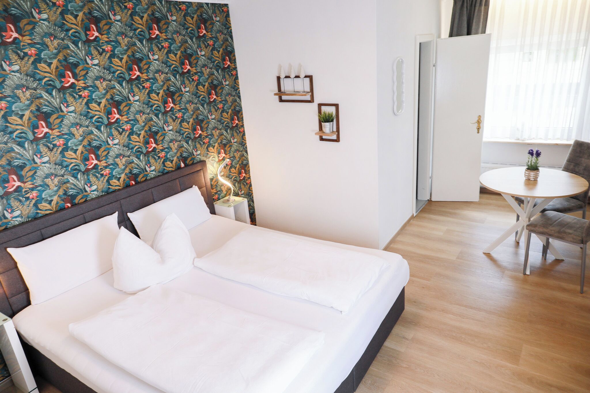 Una habitación de hotel con una cama, una mesita pequeña y una silla.