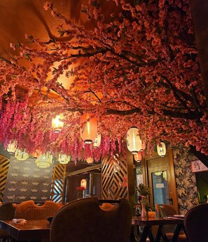 Un restaurant décoré aux motifs de fleurs de cerisier, avec des lanternes suspendues et un intérieur en bois.
