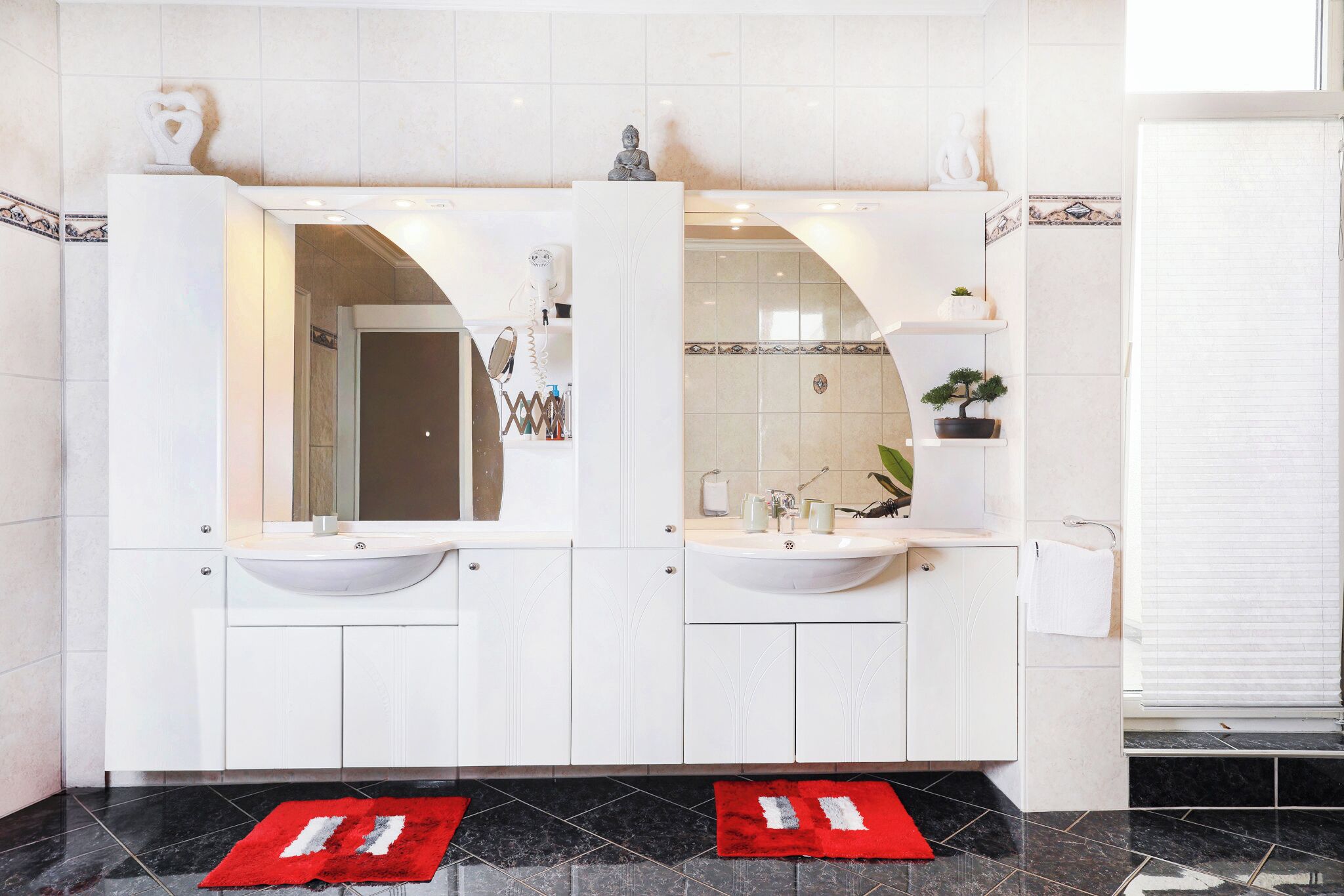 Un baño moderno con dos lavamanos, un espejo y una planta en maceta.