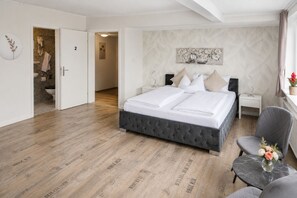 A bedroom with a bed, bedside tables, a chair, and a small table with a vase.