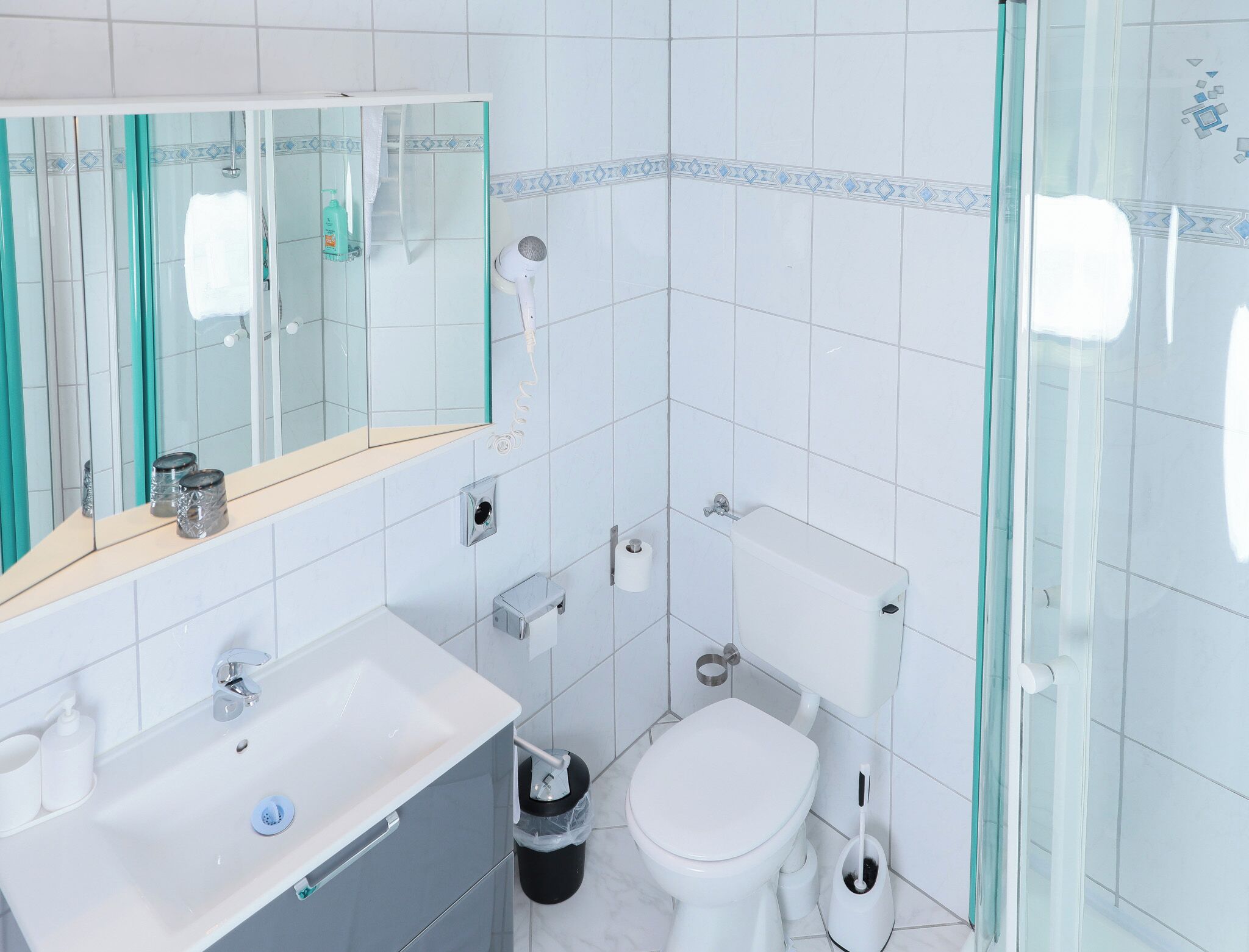 A modern bathroom with a glass shower enclosure, a white sink, and a toilet.