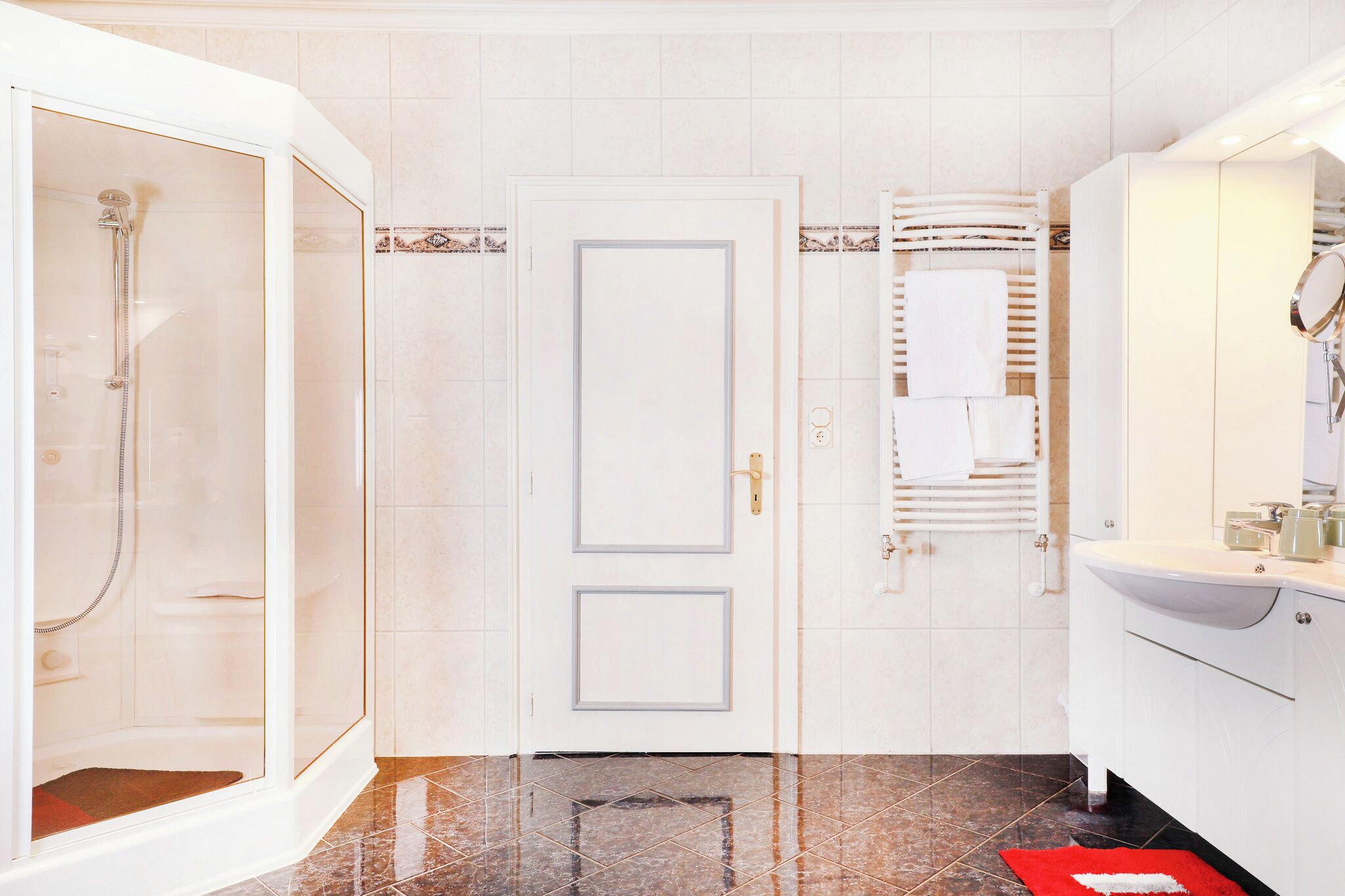 Ein Badezimmer mit Dusche, einer Tür, einem Handtuchhalter und einem Waschbecken.