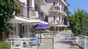 A multi-story residential building with balconies, a pool, and a patio area with outdoor furniture. - Residence La Carruba (Diano Marina)