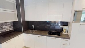 A modern kitchen with white cabinets, a black backsplash, and a built-in stove. - Modern 2P apartment with terrace in Menton (Menton)