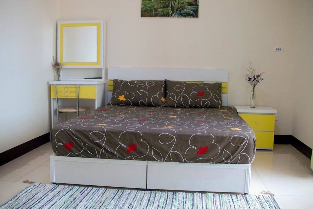 A bedroom with a bed, bedside tables, a mirror, and a painting on the wall.