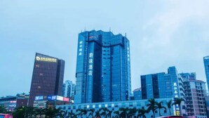A tall, modern hotel with a distinctive curved facade, surrounded by other high-rise buildings in an urban setting.