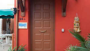 A red building with a brown door, numbered 24A, and a small balcony with potted plants. - Acqua Di Mare (Misiliscemi)