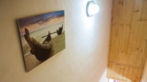 A wooden staircase leading to a room with a wooden ceiling and a wall-mounted picture of a sunset over water. - Acqua Di Mare (Misiliscemi)
