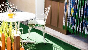 A round table with a white metal chair, a bottle of orange juice, and a small container on the table. - Acqua Di Mare (Misiliscemi)