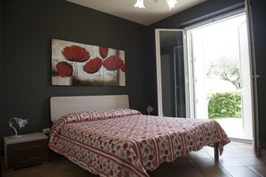 Un dormitorio con una cama, una mesita de noche, una lámpara y un cuadro en la pared.