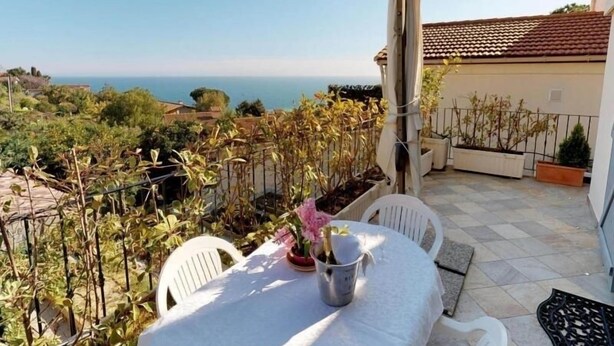 Une terrasse avec une table et des chaises, donnant sur un paysage côtier.