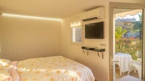 Une chambre à coucher avec un lit, un téléviseur fixé au mur et une vue sur l’extérieur.
