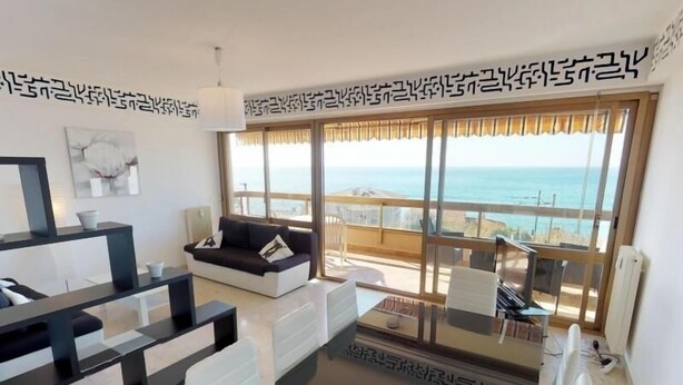 Ein modernes Wohnzimmer mit Sofa, Couchtisch und Blick auf den Ozean.
